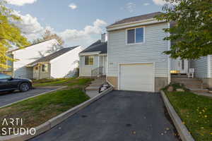 Split level home featuring entry steps, a shingled roof, a garage, and aphalt driveway