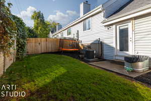 View of yard featuring central AC, a fenced backyard, and a patio
