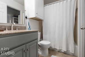 Bathroom featuring tile patterned floors, toilet, shower / bath combo with shower curtain, and vanity