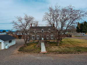 Cape cod house featuring a chimney, stone siding, and a front lawn
