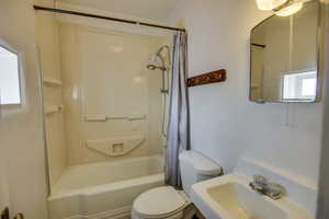Full bathroom featuring a sink, toilet, shower / tub combo with curtain, and a healthy amount of sunlight