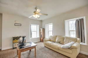 Living room featuring carpet flooring, baseboards, and ceiling fan