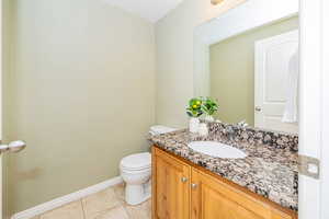 Bathroom featuring tile patterned flooring, vanity, baseboards, and toilet