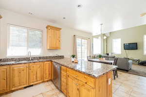 Kitchen with stainless steel dishwasher, a peninsula, visible vents, a sink, and open floor plan