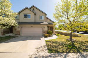 Traditional-style house with an attached garage, driveway, stucco siding, and stone siding