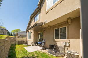 Back of property with cooling unit, a yard, a fenced backyard, stucco siding, and a patio