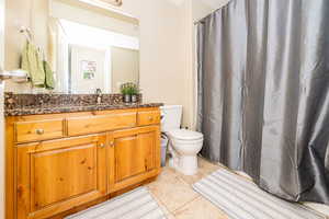 Full bathroom featuring tile patterned floors, curtained shower, vanity, and toilet
