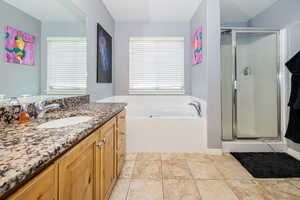 Full bathroom featuring a bath, a shower stall, and vanity