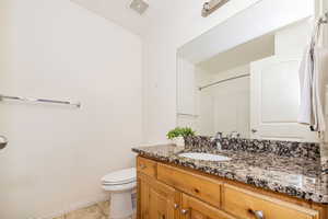 Bathroom with visible vents, baseboards, toilet, vanity, and tile patterned flooring