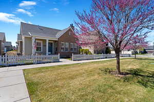 View of front of house featuring a front lawn, a fenced front yard, brick siding, a chimney, and roof with shingles