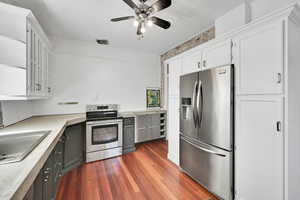Kitchen with white cabinets, masonry countertop, appliances with stainless steel finishes, a textured ceiling, and wood finished floors