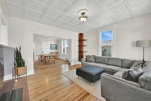 Living room featuring an ornate ceiling, recently refinished hardwood floors, baseboards, and lots of natural light.