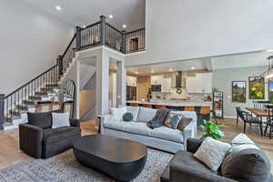 Living area with light wood-type flooring, a chandelier, recessed lighting, stairway, and a high ceiling