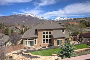 Back of house featuring a fenced backyard, a shingled roof, a lawn, and stucco siding