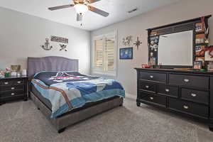 Carpeted bedroom with ceiling fan, baseboards, and visible vents