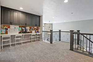 Interior space featuring recessed lighting, a kitchen bar, light carpet, and a textured ceiling