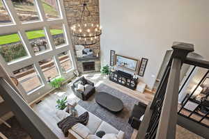 Living area featuring a high ceiling, wood finished floors, a notable chandelier, and baseboards