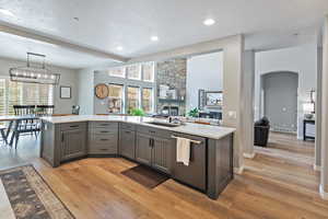 Kitchen with dishwasher, light countertops, a sink, and gray cabinets
