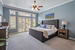 Carpeted bedroom featuring crown molding, baseboards, and multiple windows