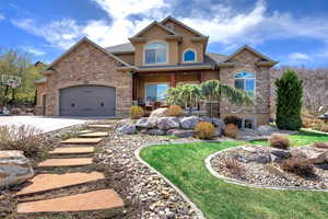 Craftsman house featuring stucco siding, driveway, stone siding, an attached garage, and a porch