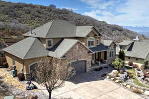 View of front of home featuring stucco siding, a mountain view, driveway, stone siding, and a garage