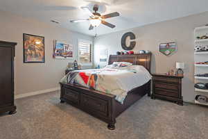 Bedroom with a textured ceiling, carpet flooring, baseboards, and a ceiling fan