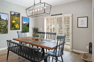 Dining space featuring visible vents, baseboards, a chandelier, and wood finished floors