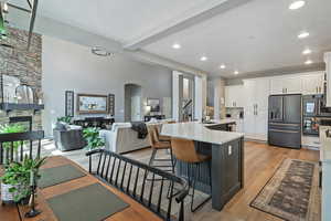 Kitchen with white cabinets, arched walkways, a stone fireplace, light countertops, and high end refrigerator