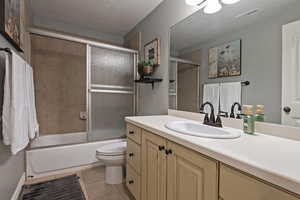 Bathroom with vanity, tile patterned flooring, a textured ceiling, toilet, and visible vents
