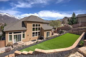 Rear view of property featuring stucco siding, a fenced backyard, a mountain view, and a shingled roof