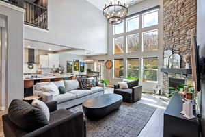 Living area with a fireplace, a notable chandelier, a high ceiling, and wood finished floors