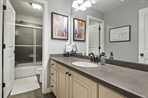 Bathroom featuring toilet, a textured ceiling, vanity, and bath / shower combo with glass door