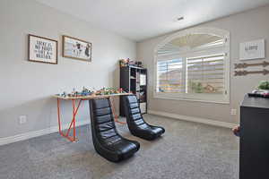 Carpeted home office featuring a textured ceiling, baseboards, and visible vents