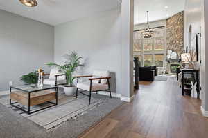 Living area with a chandelier, wood-type flooring, a high ceiling, and baseboards