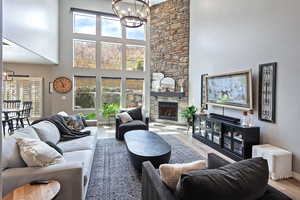 Living room featuring a high ceiling, plenty of natural light, a notable chandelier, and wood finished floors