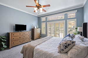 Carpeted bedroom with ornamental molding and a ceiling fan