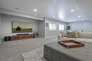 Carpeted living room featuring visible vents, baseboards, and recessed lighting