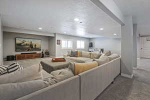 Carpeted living room featuring baseboards, recessed lighting, and a textured ceiling