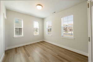 Empty room featuring light wood-style flooring, baseboards, and visible vents
