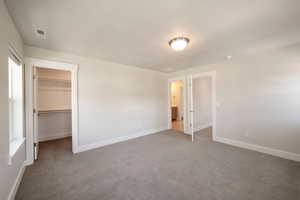 Unfurnished bedroom with visible vents, baseboards, a walk in closet, and carpet floors