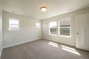 Unfurnished room featuring carpet flooring, visible vents, and baseboards