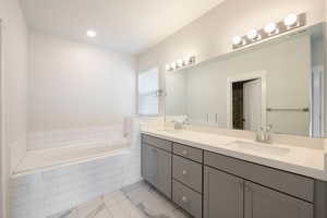 Full bathroom with a garden tub, visible vents, marble finish floor, and a sink