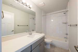 Bathroom featuring visible vents, tile patterned floors, toilet, vanity, and shower / tub combination