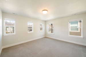 Carpeted spare room with baseboards and visible vents