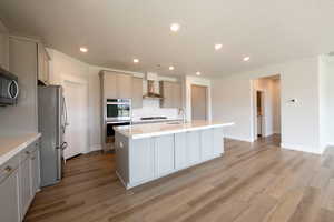 Kitchen with gray cabinets, wall chimney exhaust hood, a textured ceiling, and appliances with stainless steel finishes