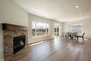 Dining room with baseboards, a fireplace, a textured ceiling, recessed lighting, and wood finished floors