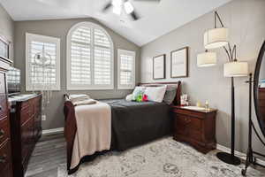 Bedroom with multiple windows, baseboards, light wood-type flooring, and lofted ceiling