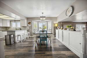 Dining room featuring a textured ceiling, a notable chandelier, dark wood-style floors, and plenty of natural light