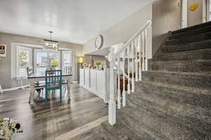 Stairway featuring a notable chandelier, baseboards, a textured ceiling, and wood finished floors