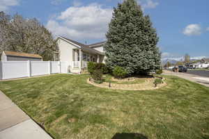 View of property exterior featuring fence and a lawn